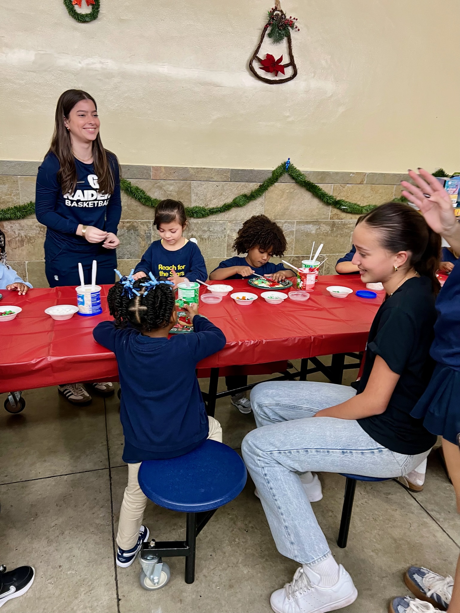 Volunteers helping children decorate cookies at festive holiday tables