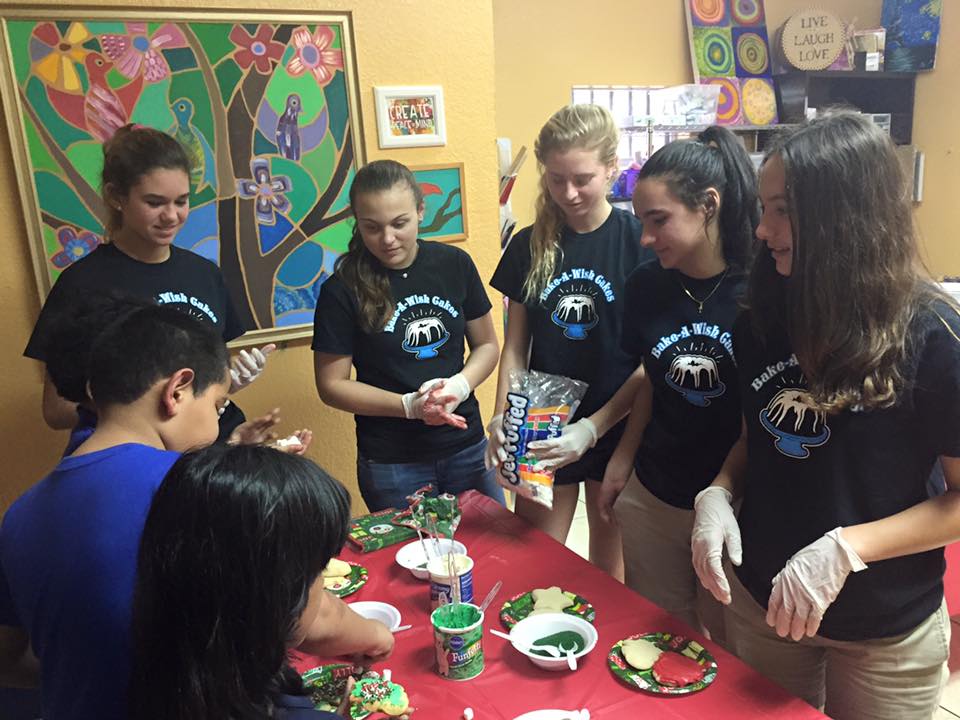 Volunteers helping children with cookie decorating in colorful classroom