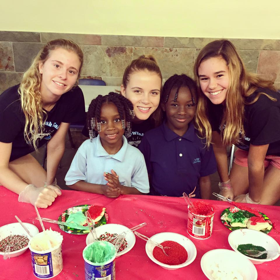 Volunteers and children at cookie decorating table with colorful frosting