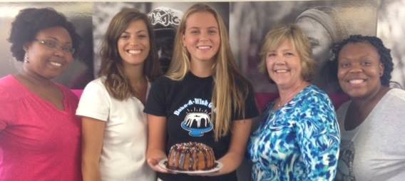 Group of five women volunteers with one holding decorated bundt cake