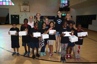 Bake-A-Wish volunteers and children holding certificates in school gymnasium