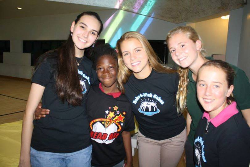 Bake-A-Wish volunteers with child in Read On! t-shirt in gymnasium setting