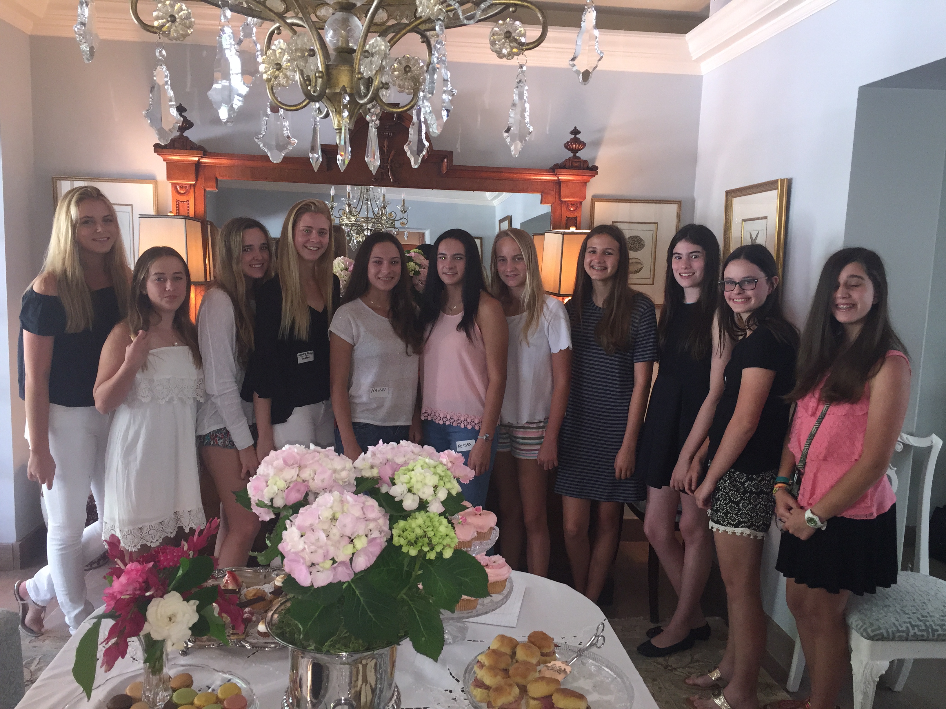 Large group of volunteers at elegant gathering with flowers and treats