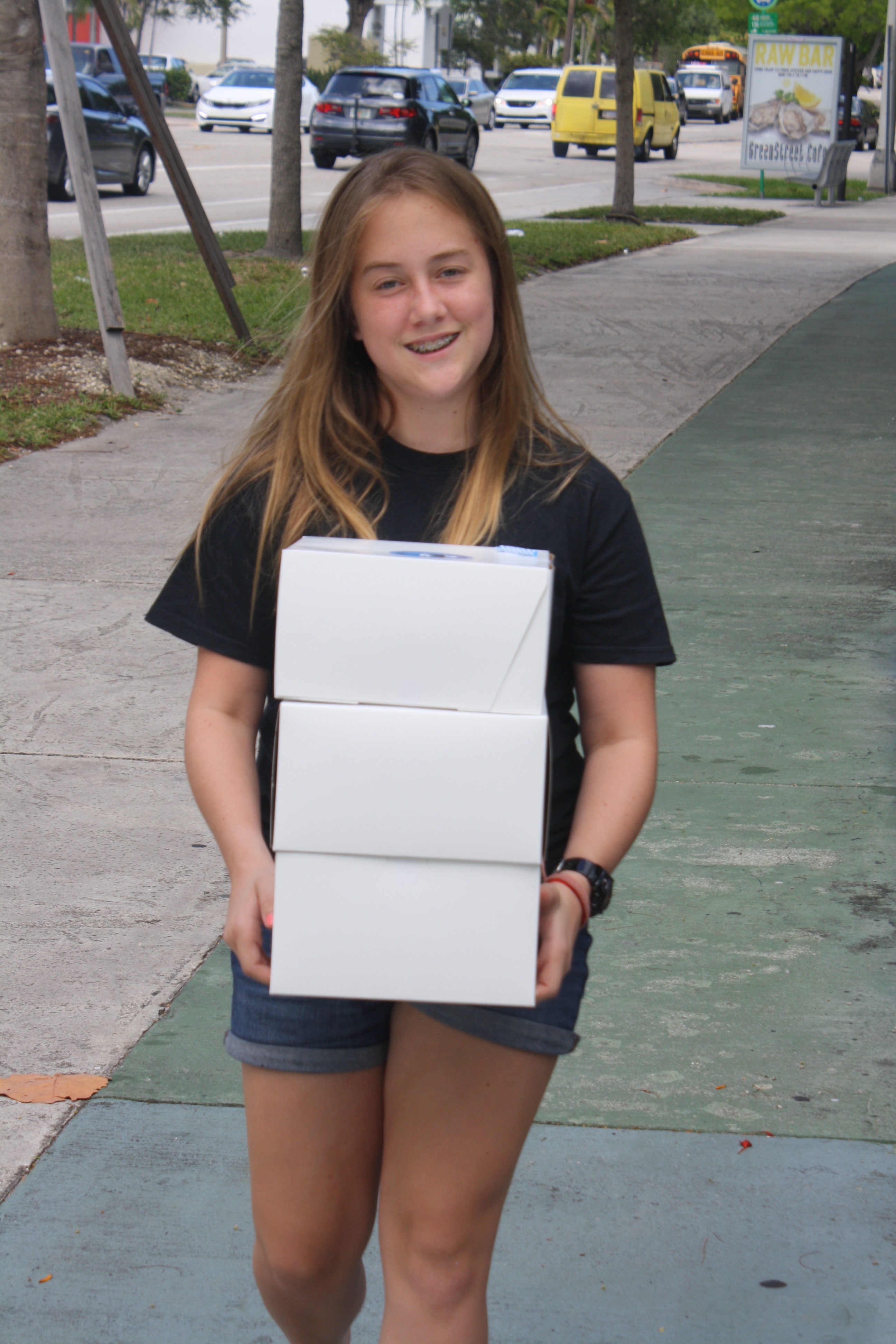 Young volunteer carrying stack of cake boxes for delivery